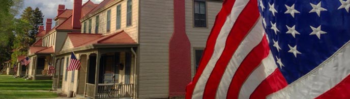 An American flag flutters in front of historic yellow and red buildings An American flag flutters in front of historic yellow and red buildings