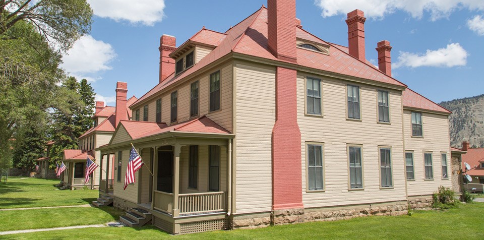 A row of three story buildings with wood siding, red roofs, and tall brick chimneys.