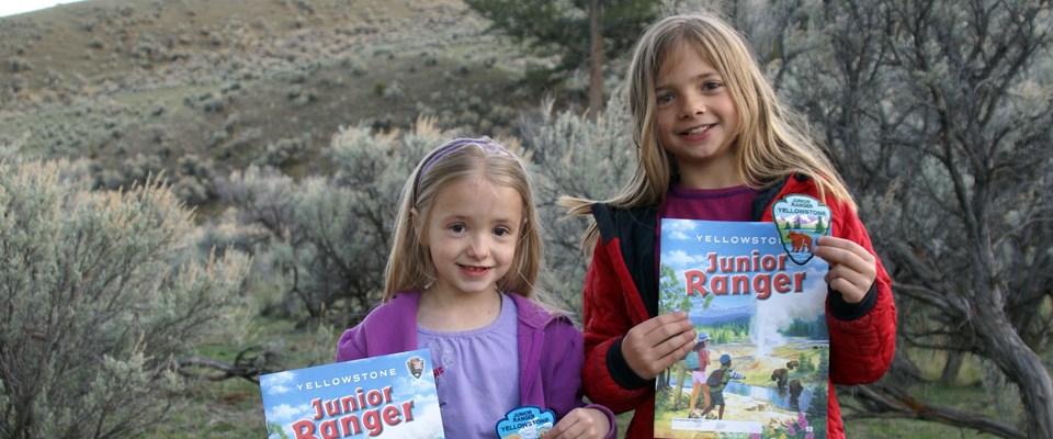 Two young junior rangers hold up their books and patches Two young junior rangers hold up their books and patches