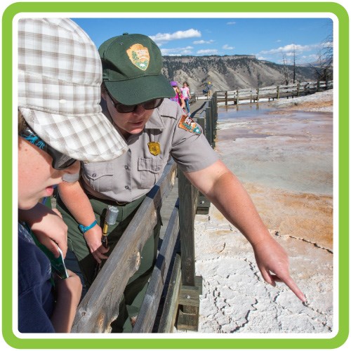A ranger talks with a visitor and points out a hydrothermal feature.