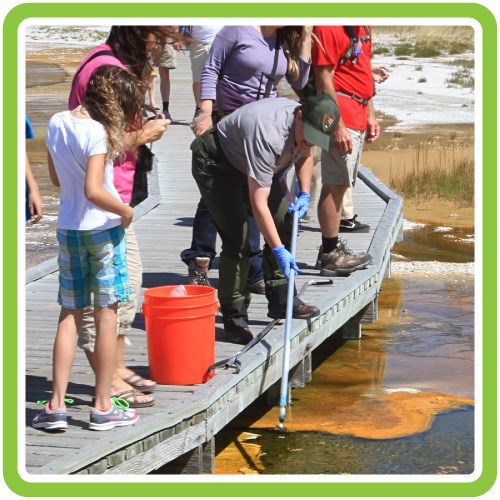 Ranger using a tool to clean trash from a hot spring.