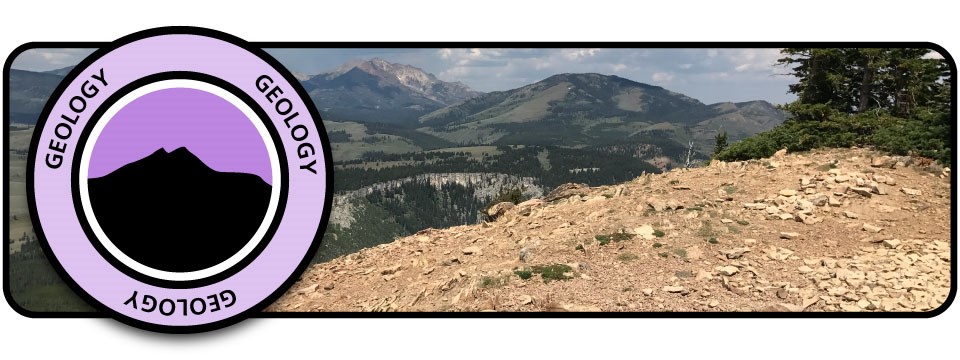 Geology header with badge Purple badge with silhouette mountain and word "Geology" over image of a rock mountaintop overlooking other mountains.