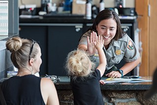 A park ranger high fives a young visitor
