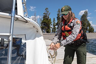 A park ranger unties a boat from a dock