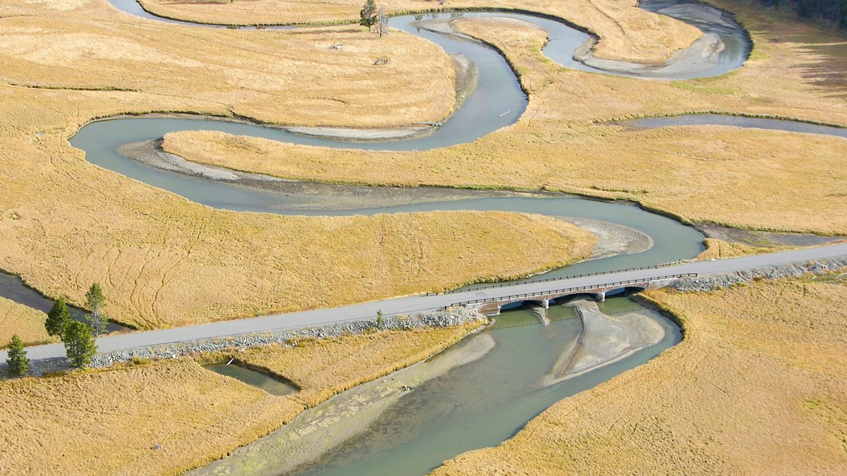 an aerial view of a bridge over a winding creek