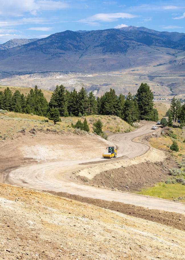 construction vehicles building a brand-new road through a mountainous area