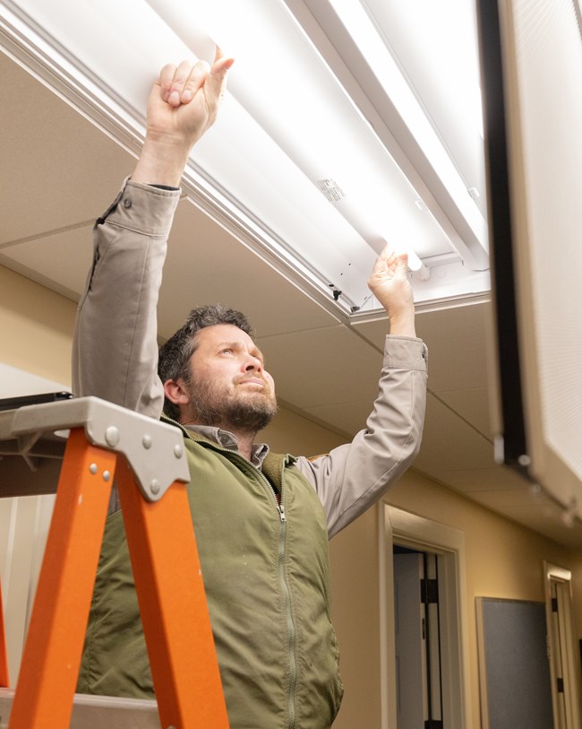 a person replacing light bulbs in a ceiling