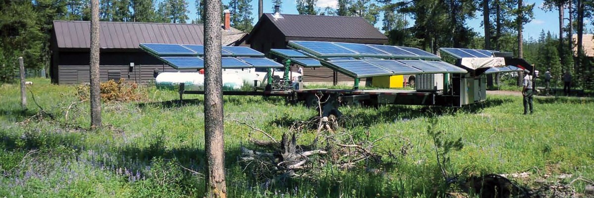 Solar panels unfolded from a trailer next to a ranger station