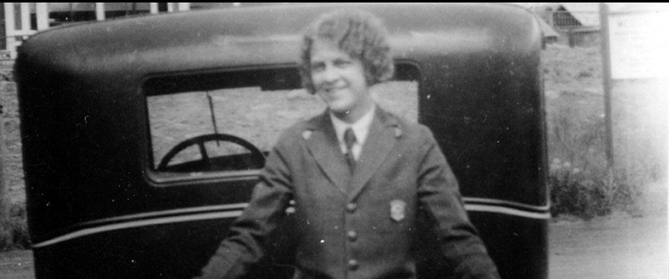 A ranger poses in front of a car