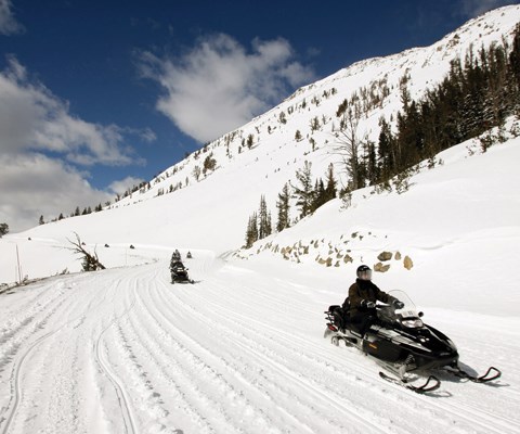A line of snowmobiles spread out on a mountain road