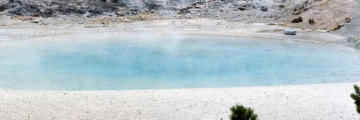 A blue steaming pool surrounded by pale rock A blue steaming pool surrounded by pale rock