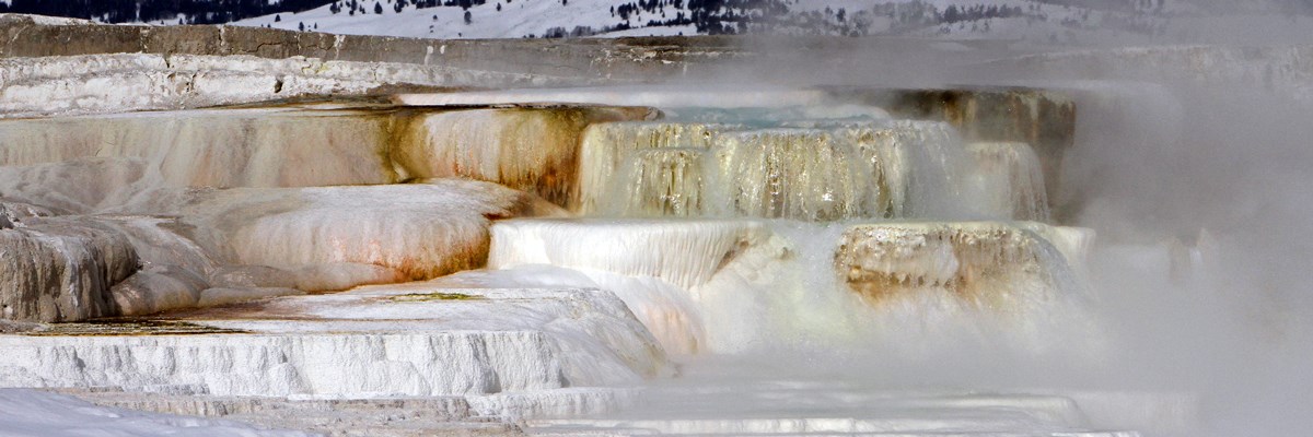 White and orange rocks form steps filled with steaming pools of cloudy water White and orange rocks form steps filled with steaming pools of cloudy water