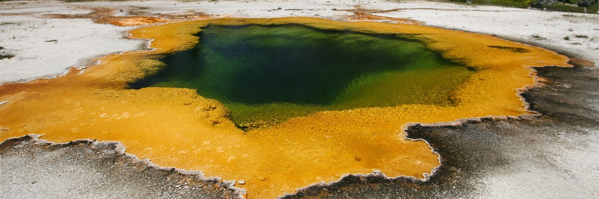 A hot spring with deep blue water and bright yellow edges