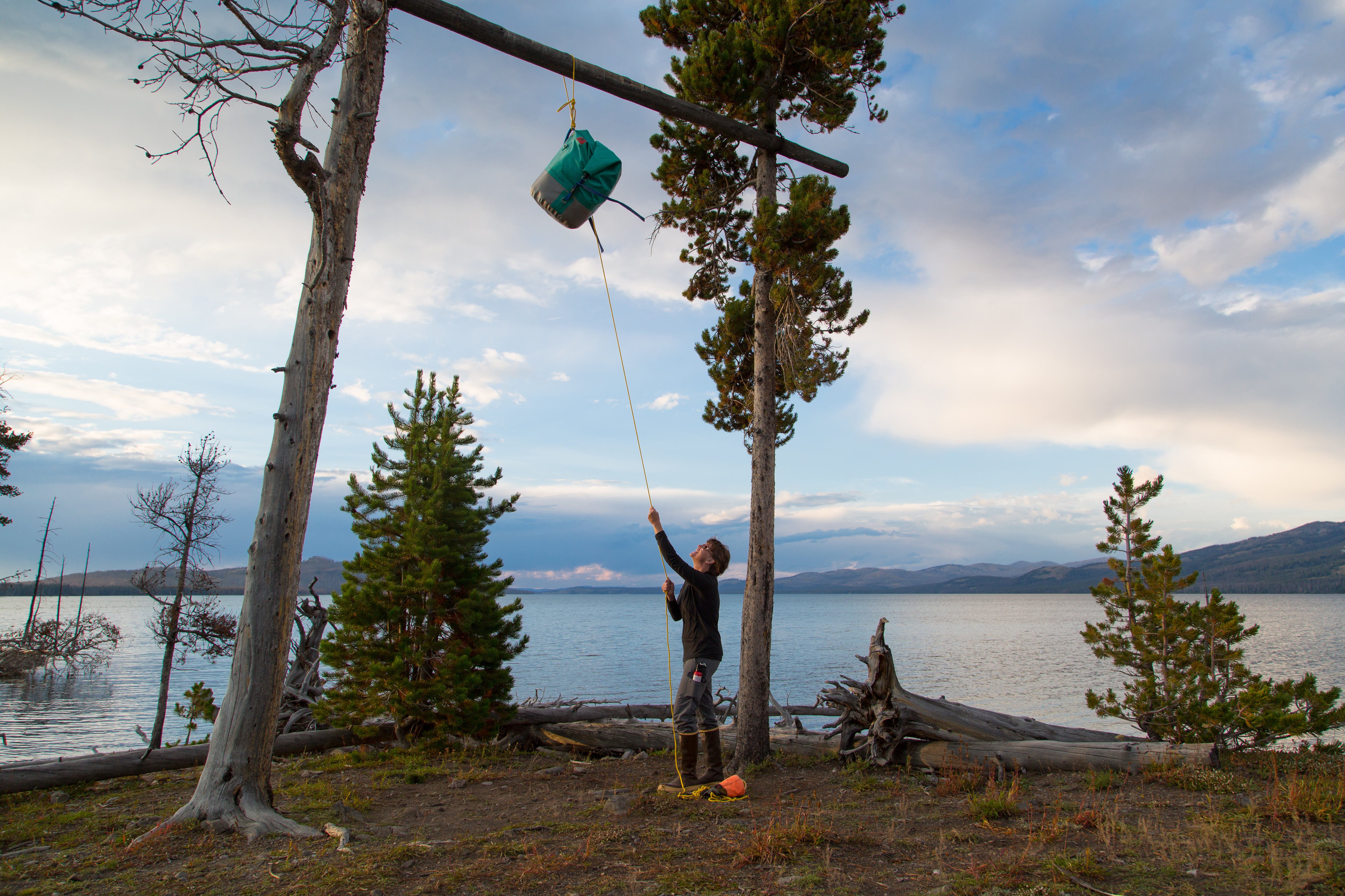 A camper hanging food on a food pole at a park campsite.