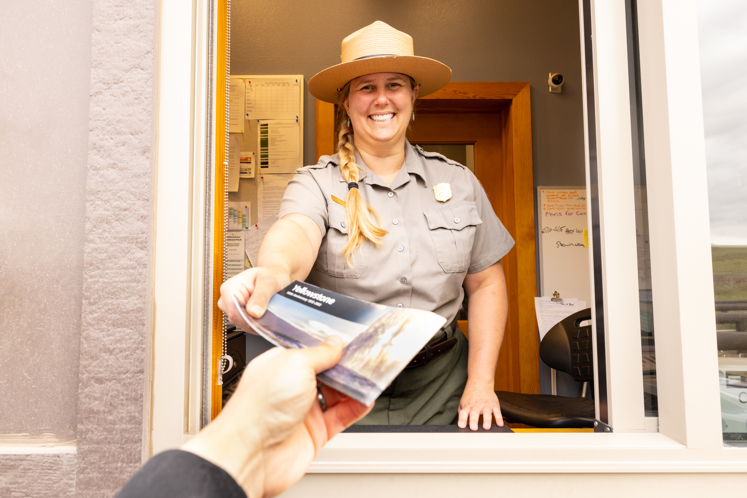 a park ranger handing out a newspaper at an entrance station