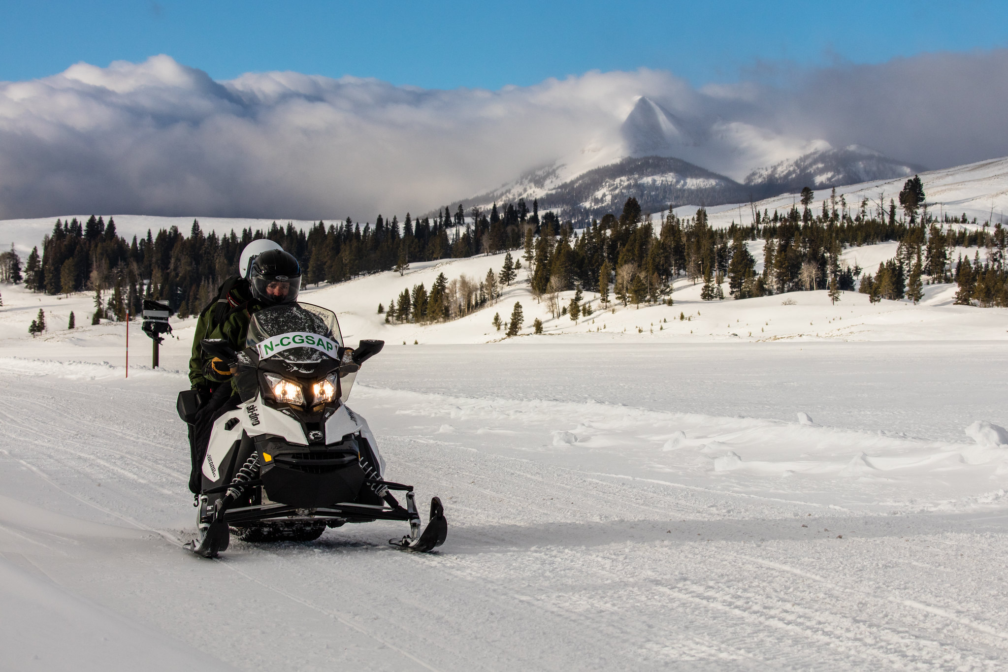 Two people on a snowmobile in a wintry landscape