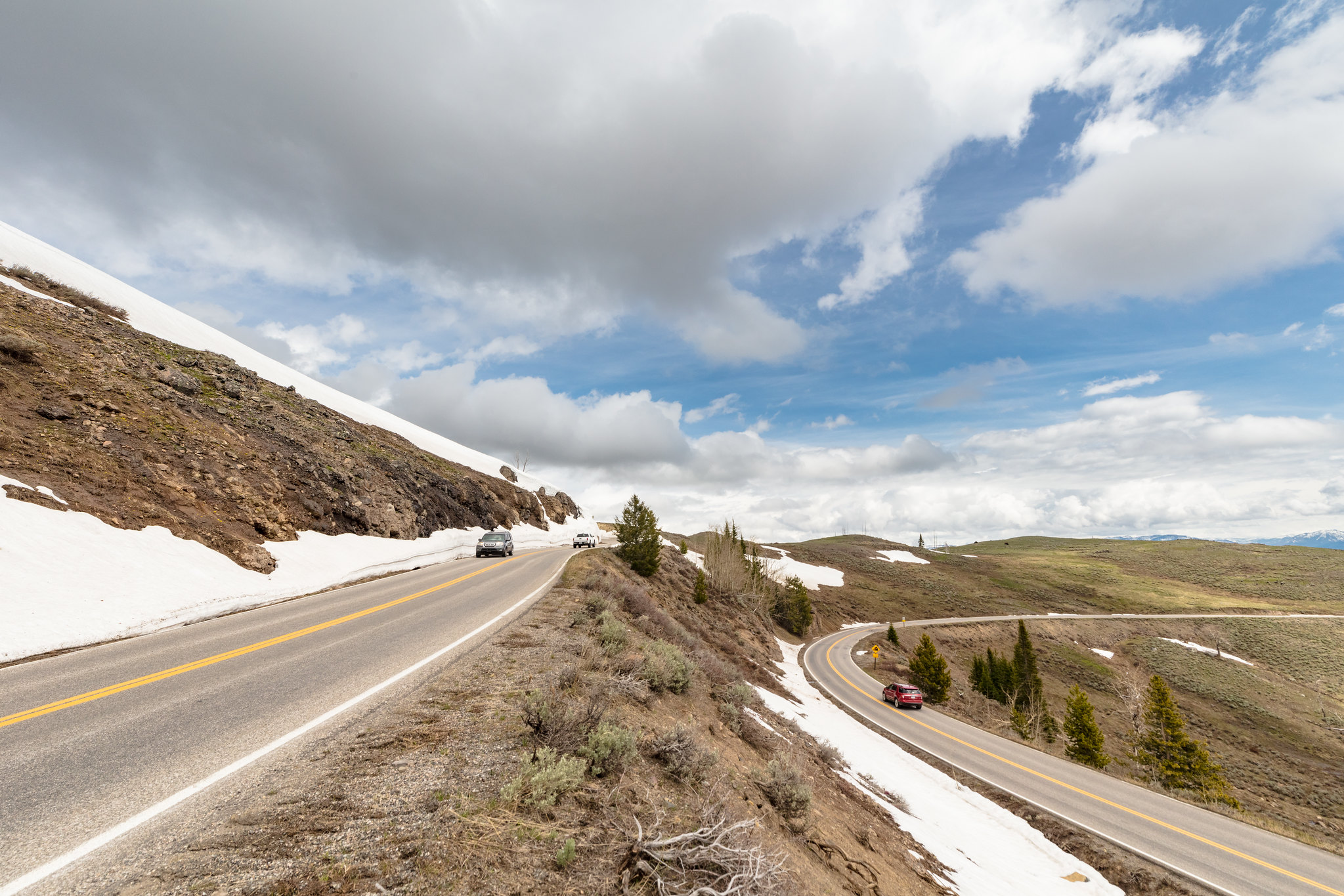 Cars driving along a high, mountain road with snow