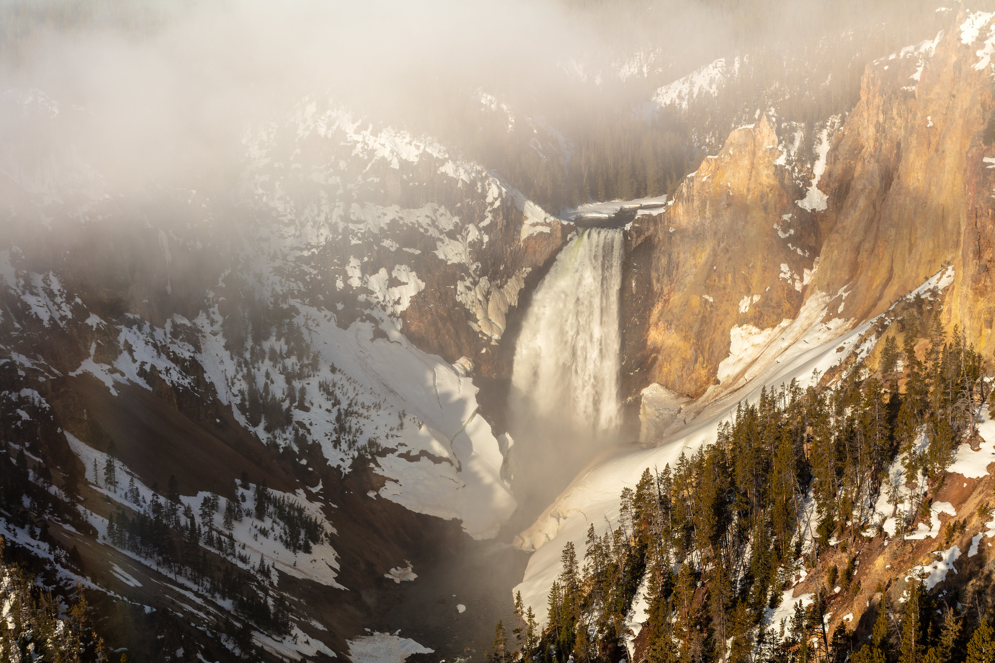 waterfall with snow on the sides of canyon