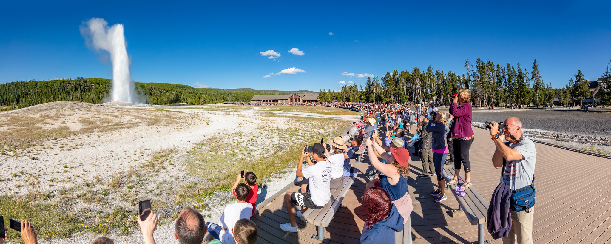 A group of people watch an Old Faithful eruption