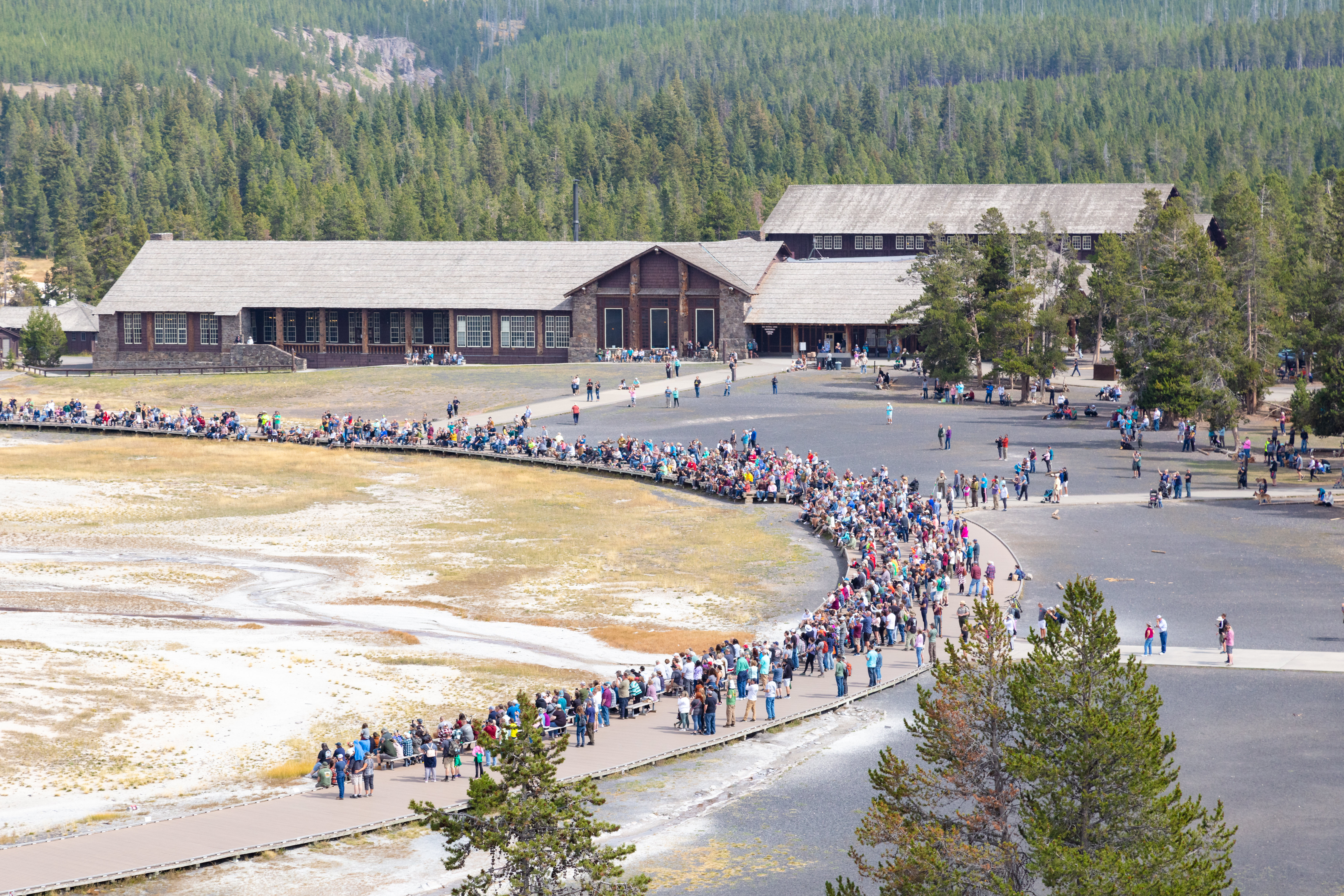 Crowds of people wait for an Old Faithful geyser eruption