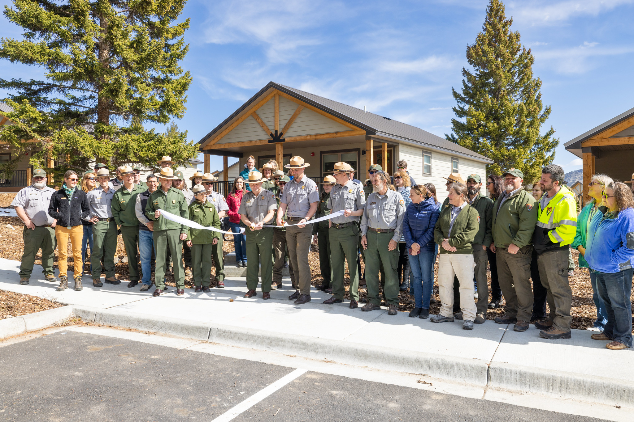 a group of Yellowstone employees cutting a ribbon in front of new park housing