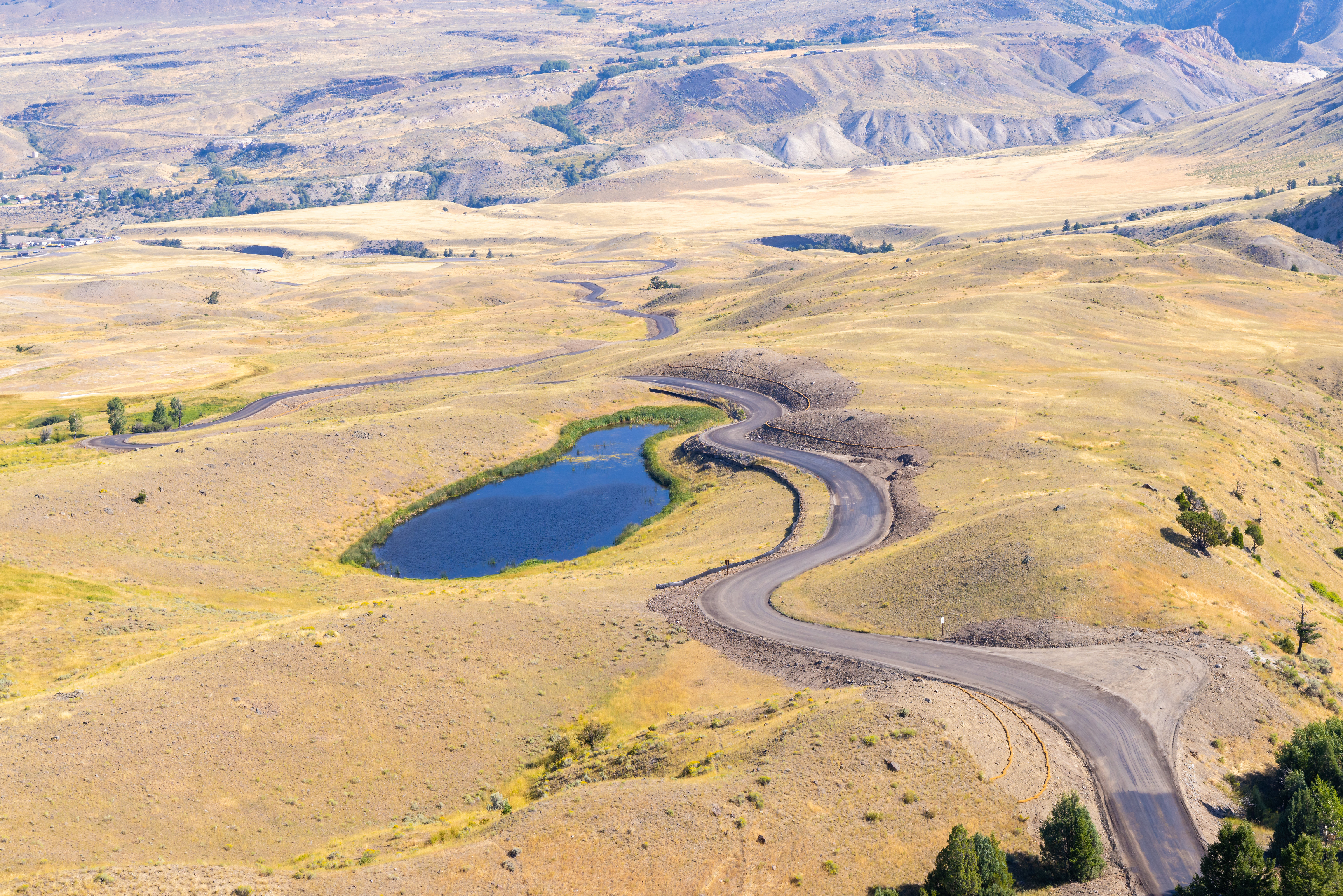 a winding paved road through a hilly landscape