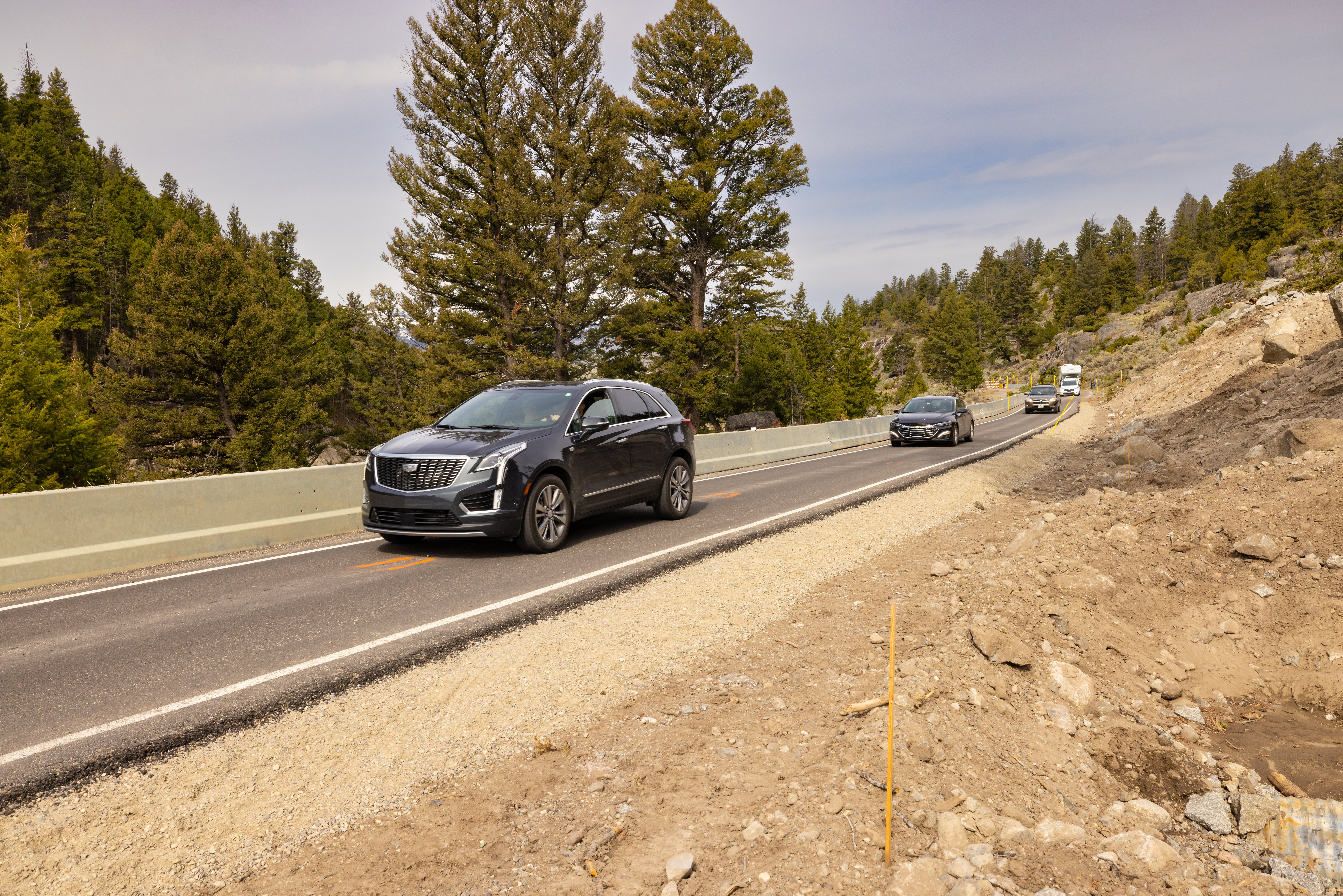 vehicles driving on a one-lane, paved road through a canyon