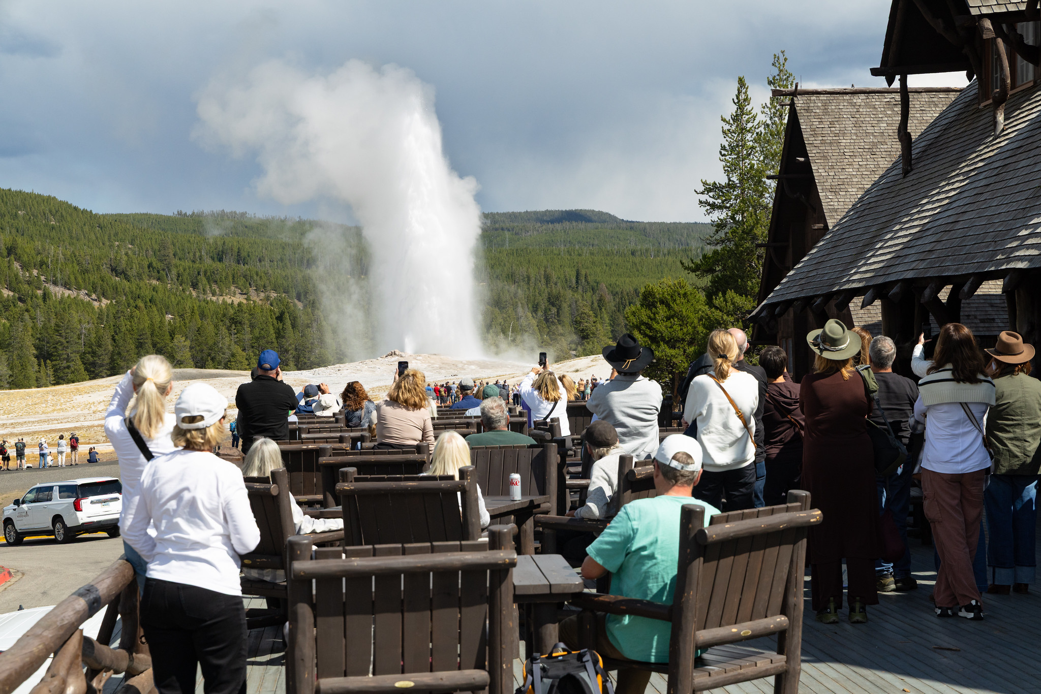 People enjoy a view of Old Faithful from the outside deck at the Inn