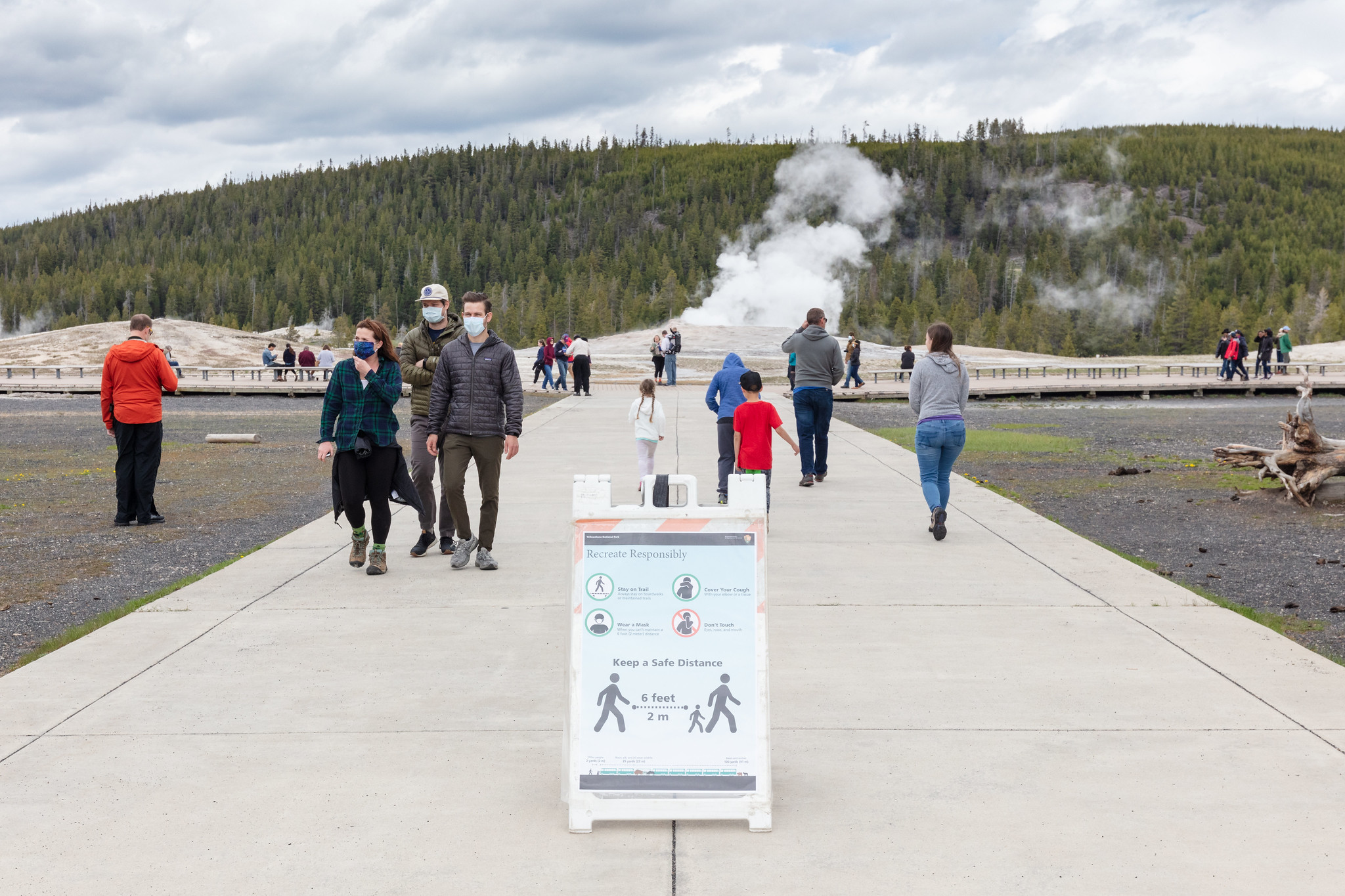 OF Visitors wearing masks and social distancing in front of Old Faithful Geyser