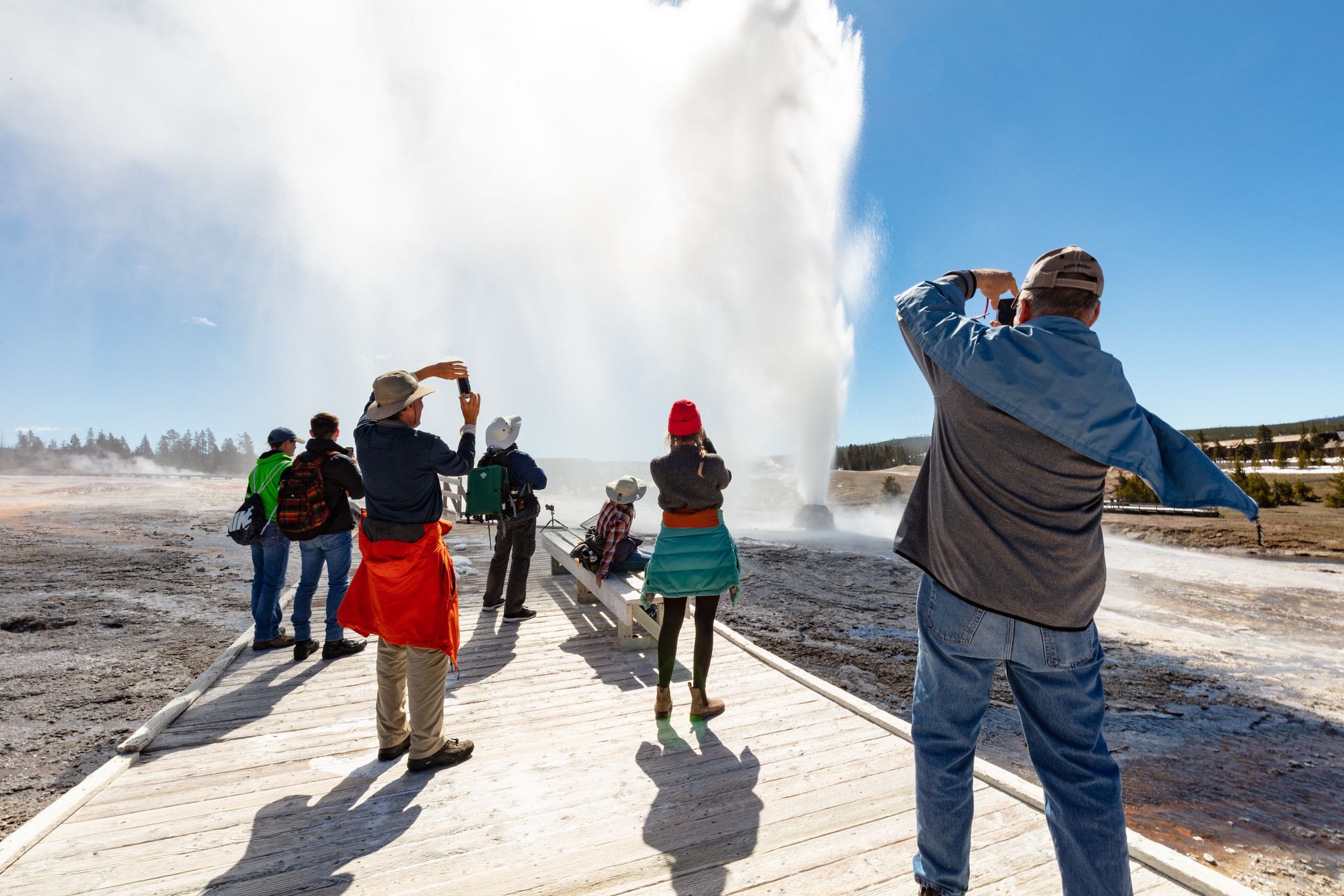 A group watches and photographs a Beehive Geyser eruption