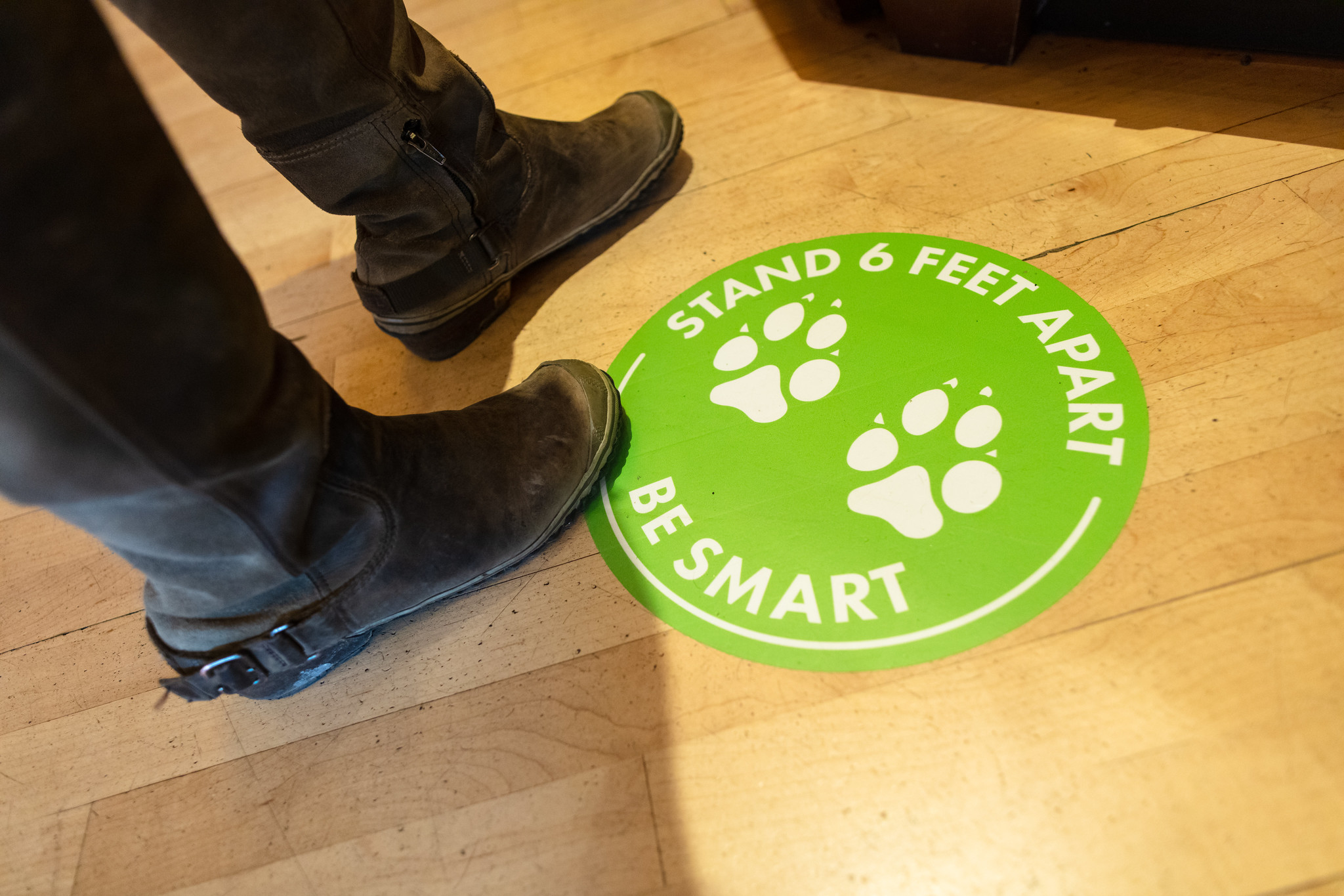 foot visitor standing on a decal that asks people to social distance
