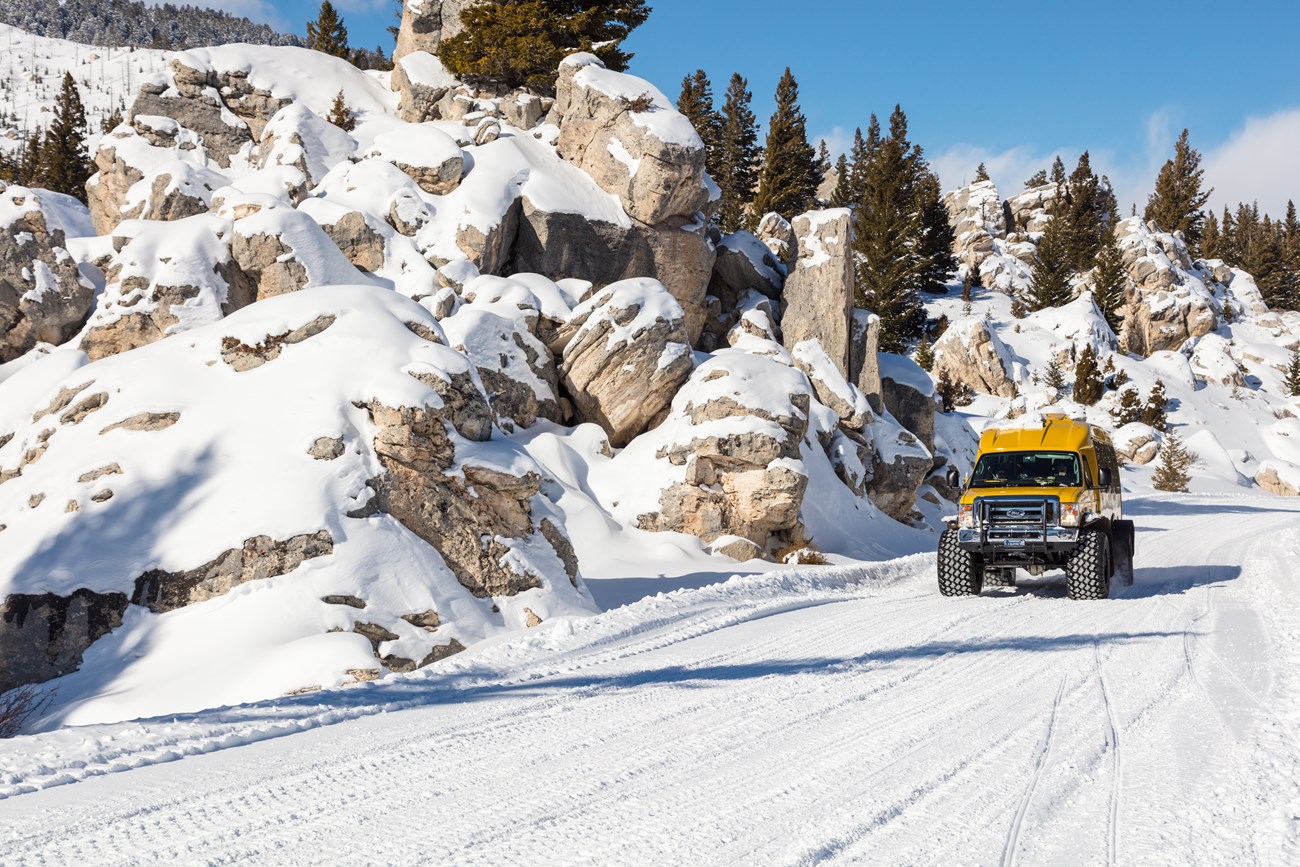 Snowcoach in the Hoodoos A snowcoach moves along a snowy road between rock outcroppings