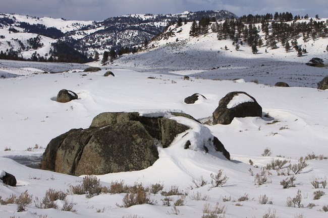 Large boulders dot the valley, both covered in snow.