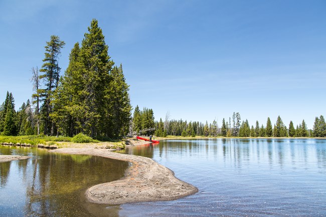 Canoeists stand on the shore of Lewis Lake.