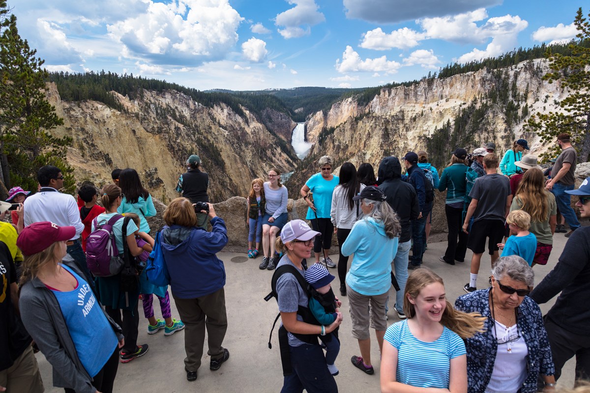 Dozens of people at an overlook with a view of a waterfall Dozens of people at an overlook with a view of a waterfall