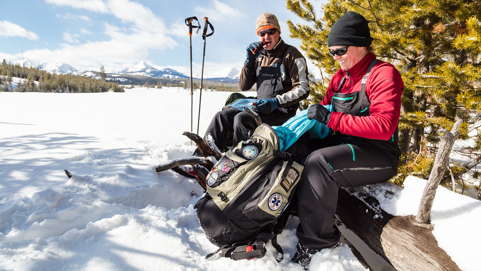 Two skiers change layers and eat while out for a ski