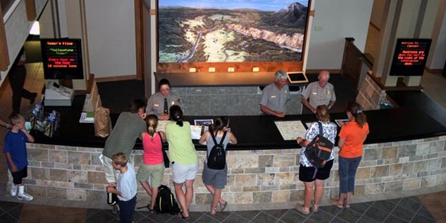 View from a balcony of families talking to rangers at a desk