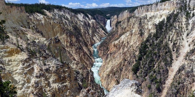 A canyon with tan walls and a waterfall