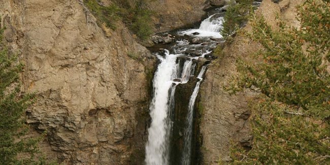 A stream of water falls from brown rock