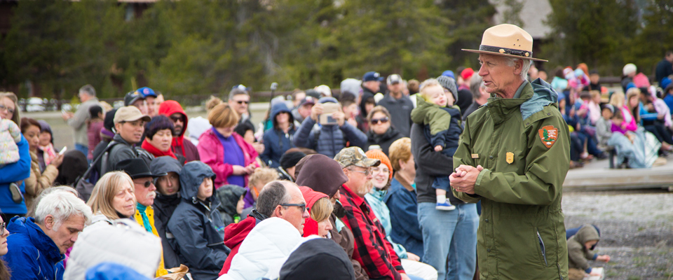 A male park ranger speaks to a seated crowd A male park ranger speaks to a seated crowd