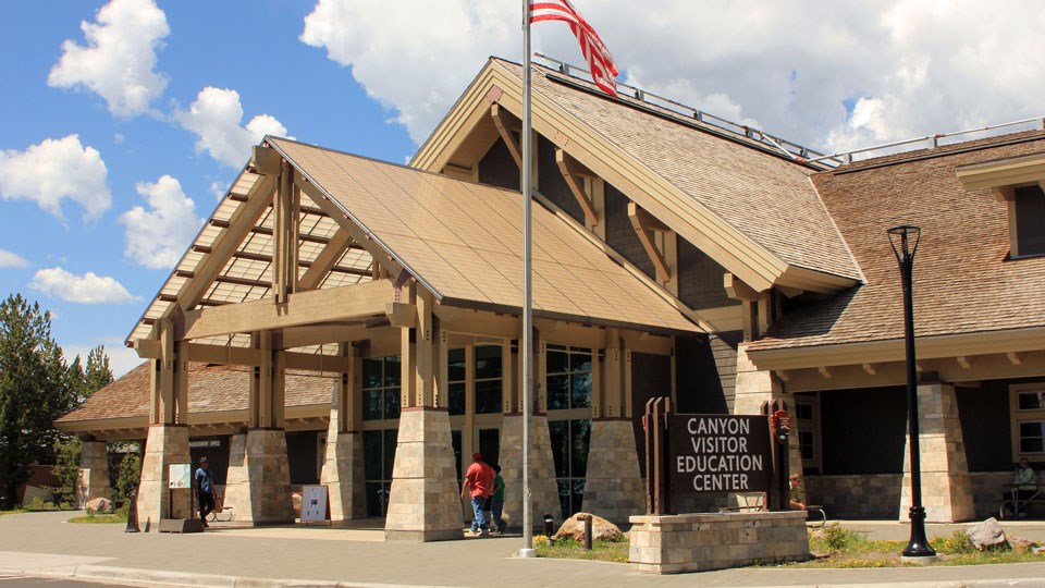 Visitors walk toward the entrance of the wood and stone visitor center.