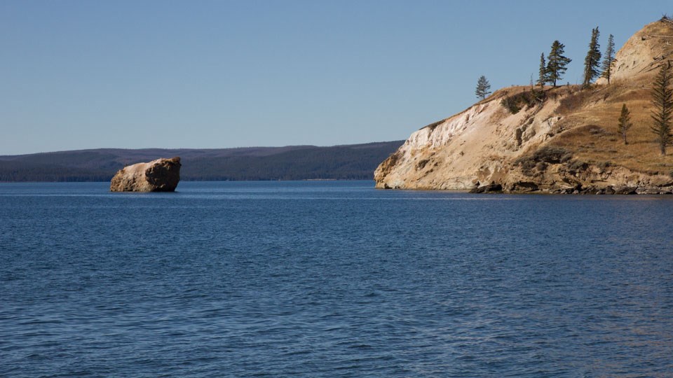 Yellow cliff drops down into the blue waters of Yellowstone Lake Yellow cliff drops down into the blue waters of Yellowstone Lake