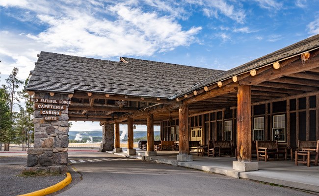 A rustic lodge in front of a geyser basin with the sign: Old Faithful Lodge