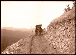 A horse-drawn buggy on a mountain dirt road.