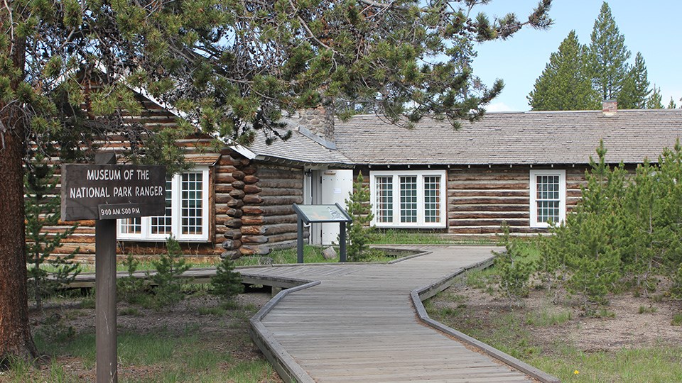 A wooden boardwalk leads to a log building