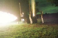 Color photograph of the firing of a cannon at night.