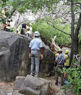 Search and rescue team use ropes to lower litter off a boulder
