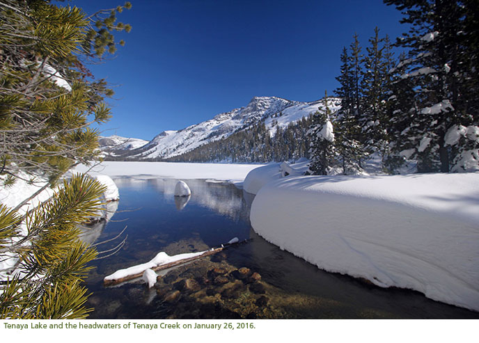 An ice covered, alpine lake near the mouth of a creek.