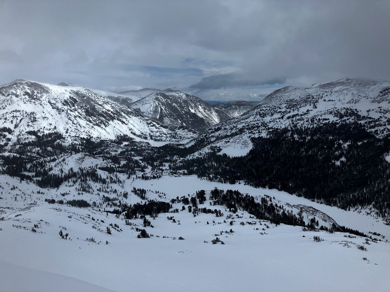 View from above looking down a snowy canyon with a few snow-covered lakes on a cloudy day View from above looking down a snowy canyon with a few snow-covered lakes on a cloudy day