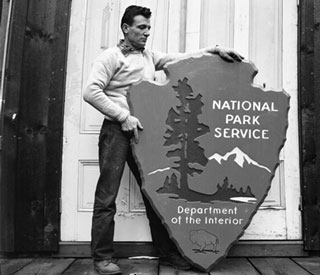 arrowhead sign Man standing next to National Park Service arrowhead